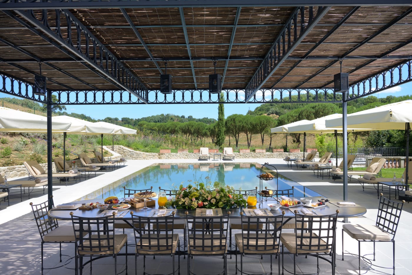 Café da manhã servido sob uma pérgola de frente para a piscina da propriedade Viesca Toscana