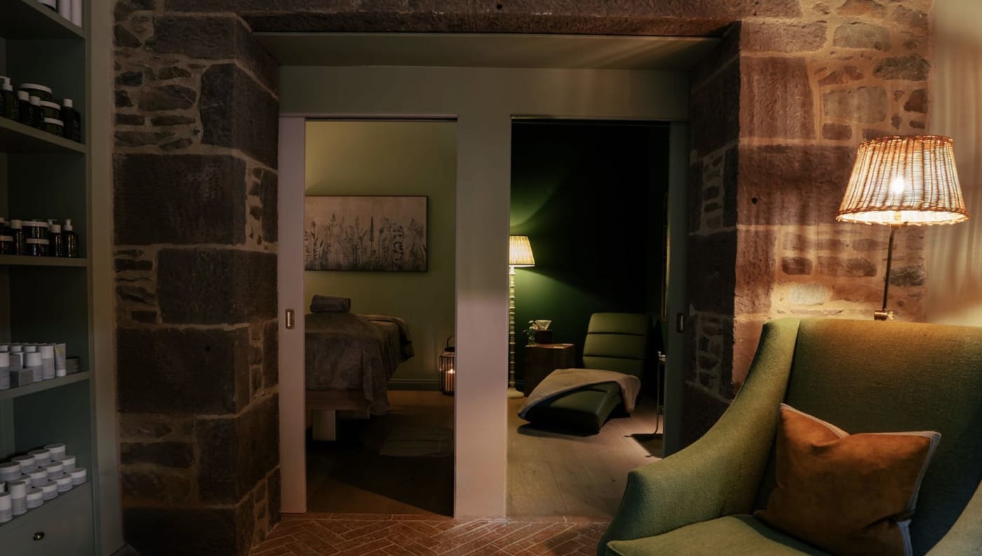 Cabine de soins du Woodland Retreat de l'hôtel Cromlix, murs de pierre et fauteuil de velours vert