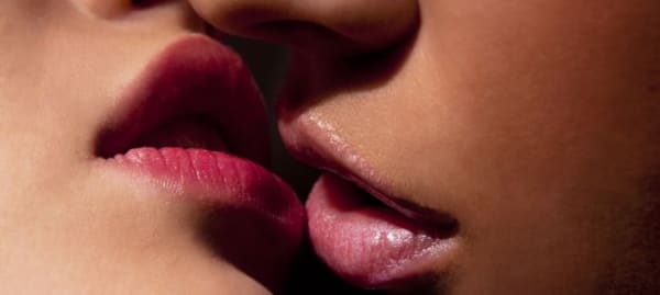 Close-up of a couple with parted lips about to kiss.