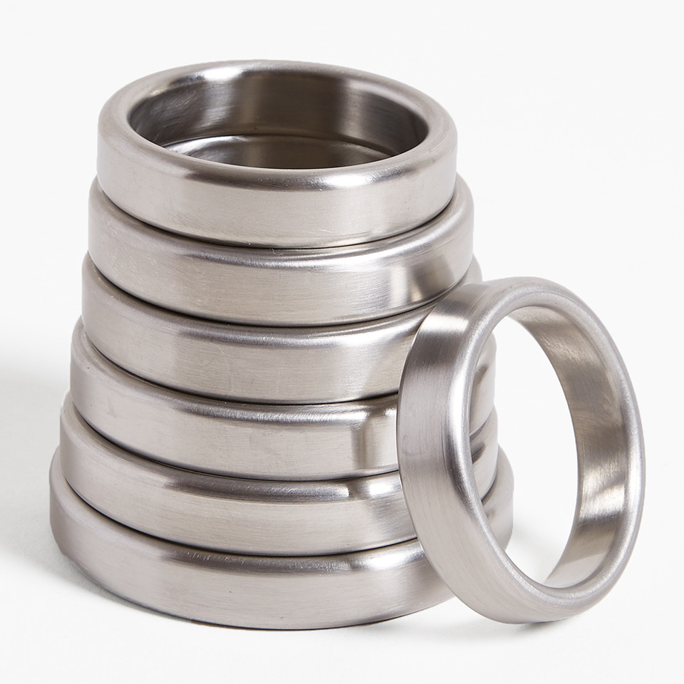 Hand holding a stack of shiny stainless steel cock rings of various sizes