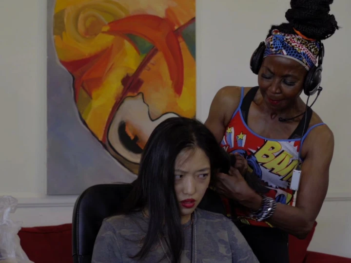 Young girl getting hair braided at black salon