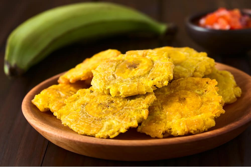 Tostones, fried and flattened pieces of green plantains, are a traditional snack or accompaniment in Cuba