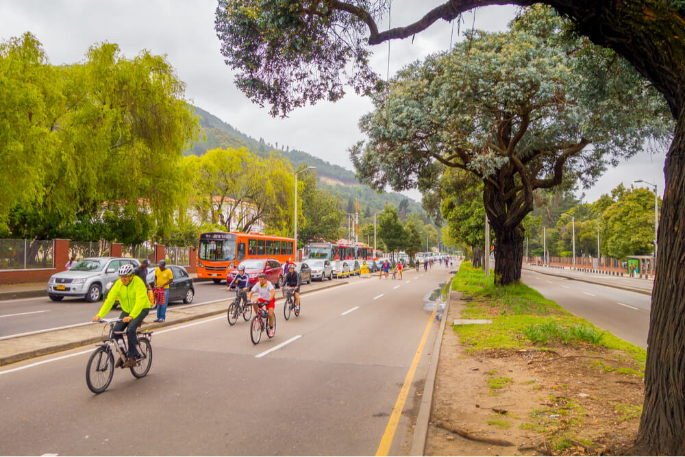 Cyclists moving through a vehicle-free street with heavy traffic in the opposite lane in Candelaria area Bogota, Colombia