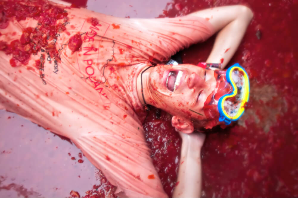 A young man laughing, lying in crushed tomatoes at the Tomatina festival in Buñol, Spain, on August 28, 2013
