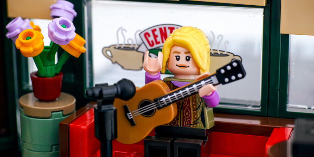 Lego Phoebe Buffay minifigure performing songs on guitar in Central Perk cafe.