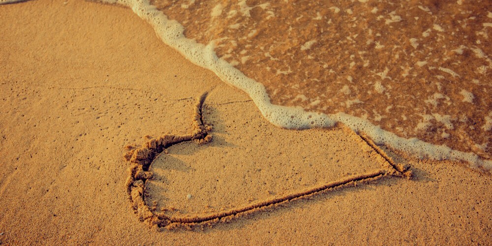 Heart on a beach washed off by a wave