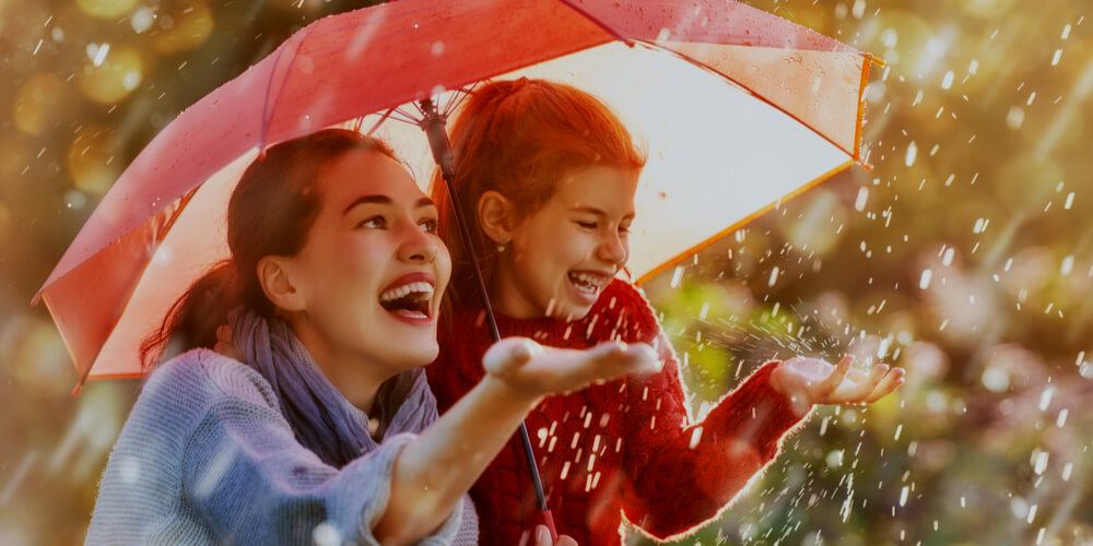 Mother and daughter under rain