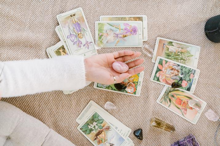 woman holding a crystal with tarot cards behind her hand