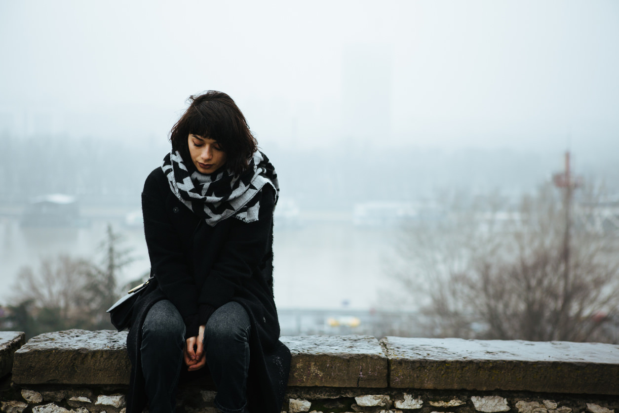 Girl sitting on edge of a stone wall 