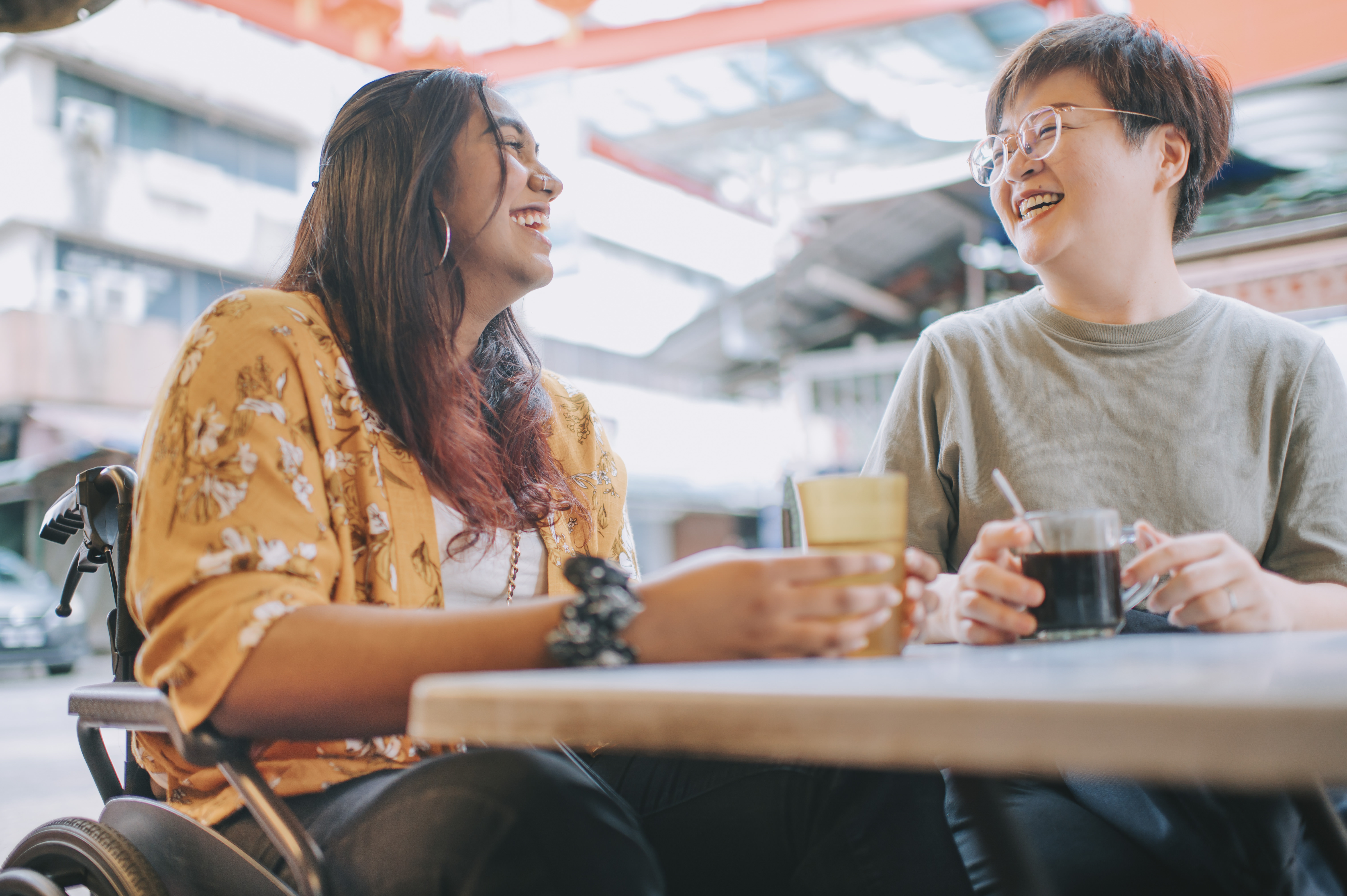 Women in wheelchair having coffee with friend Women in wheelchair having coffee with friend