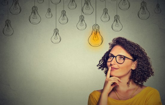 Woman thinking with light bulbs in background