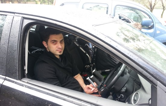 Man sitting in car with assistive steering wheel Man sitting in car with assistive steering wheel