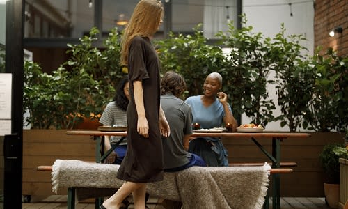 Woman walking past a table wearing a icebreaker merino dress