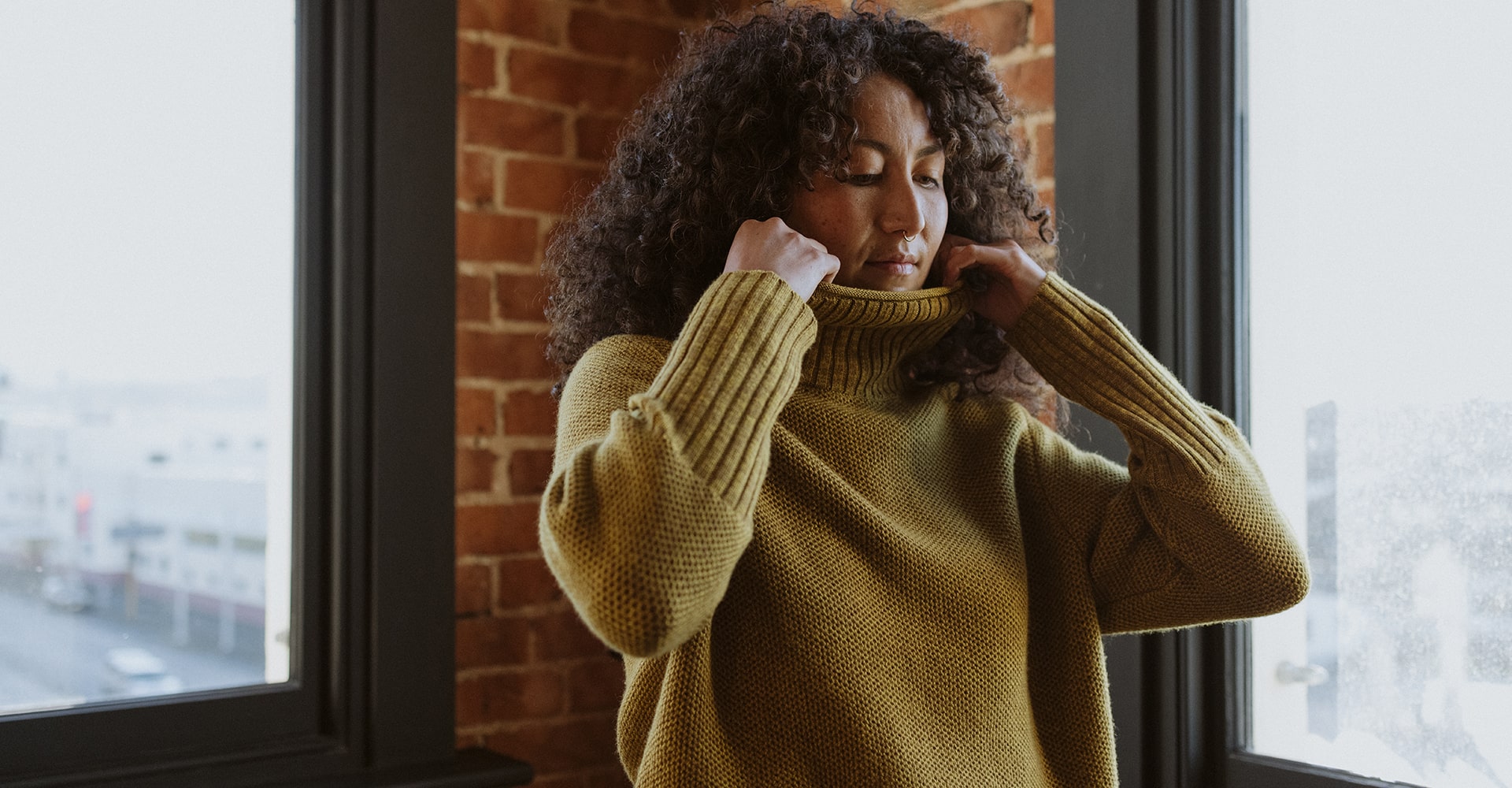 Woman standing inside wearing icebreaker seveesta roll neck knitted sweater