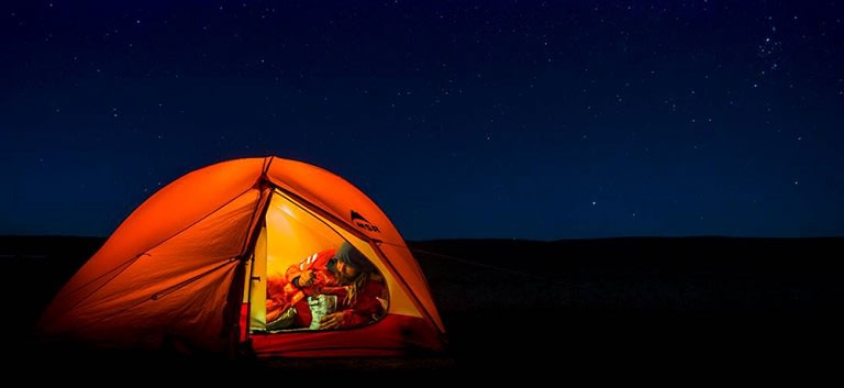 Mateusz Waligóra inside illuminated tent during pitch dark night