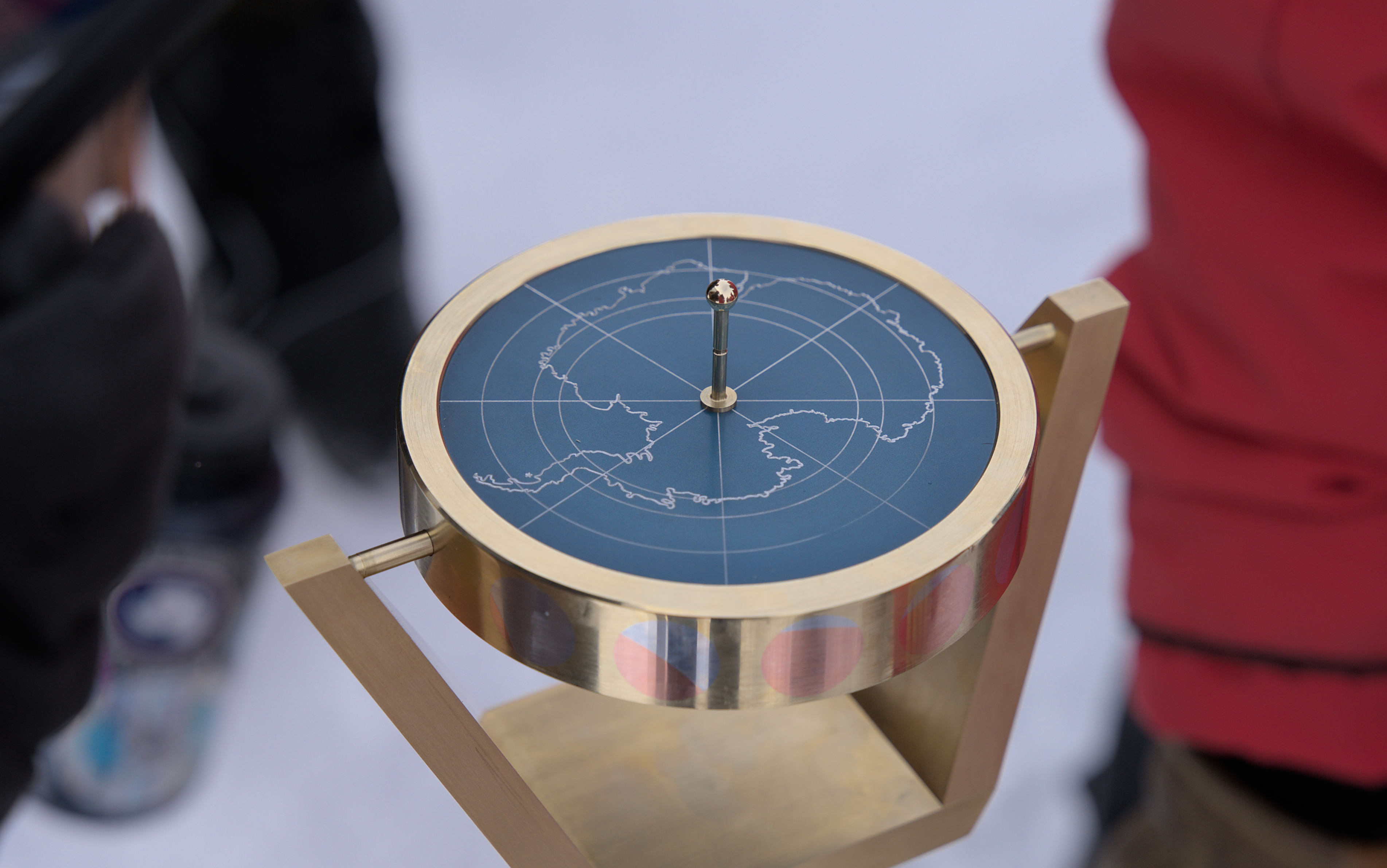 Close-up of top side of South Pole marker, with sundial on outline of Antarctica.