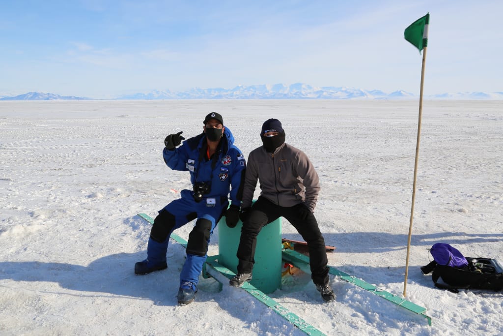 Two new winterovers, seated for a photo out on the ice.