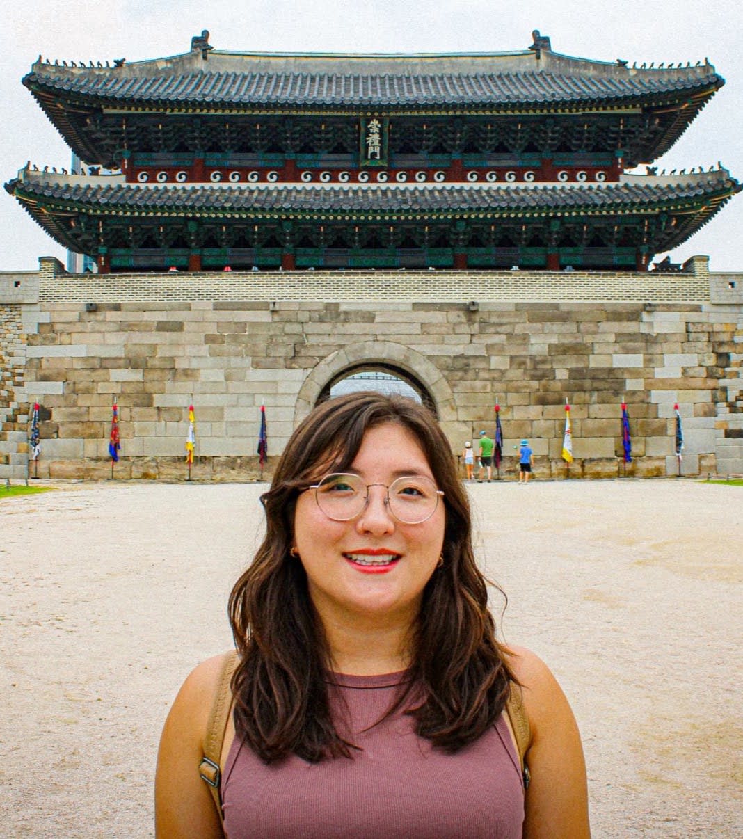 A headshot of a woman standing in front of a temple.