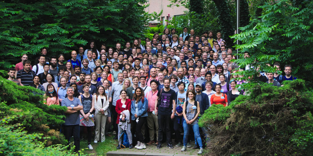 A large group of people standing outside next to some trees