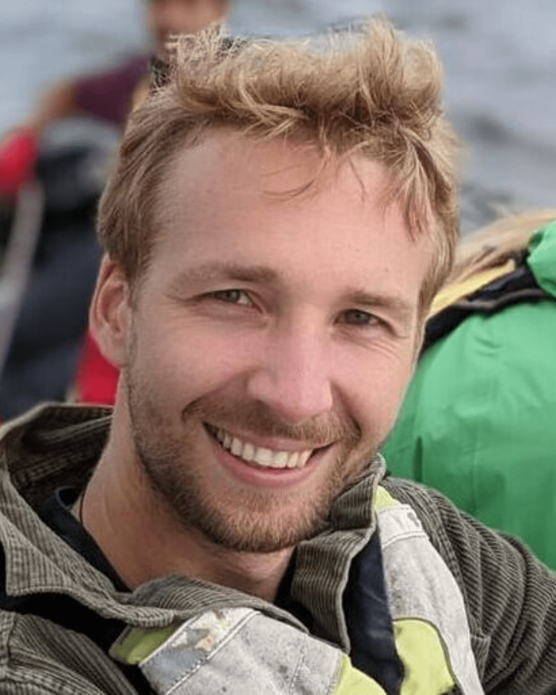A man with a grey jacket smiling and posing for a photo.