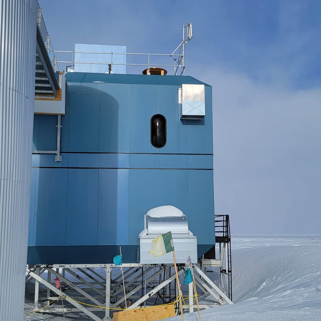 Side view of IceCube Lab with newly mounted wind turbine on top corner of roof.