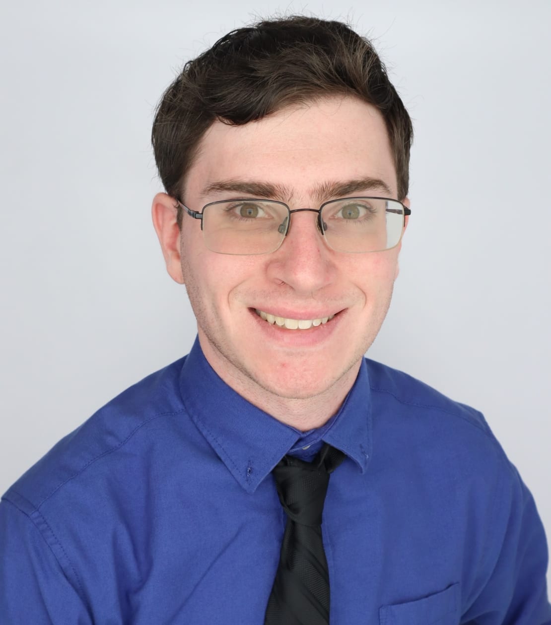 A man with glasses and a blue shirt posing for a photo
