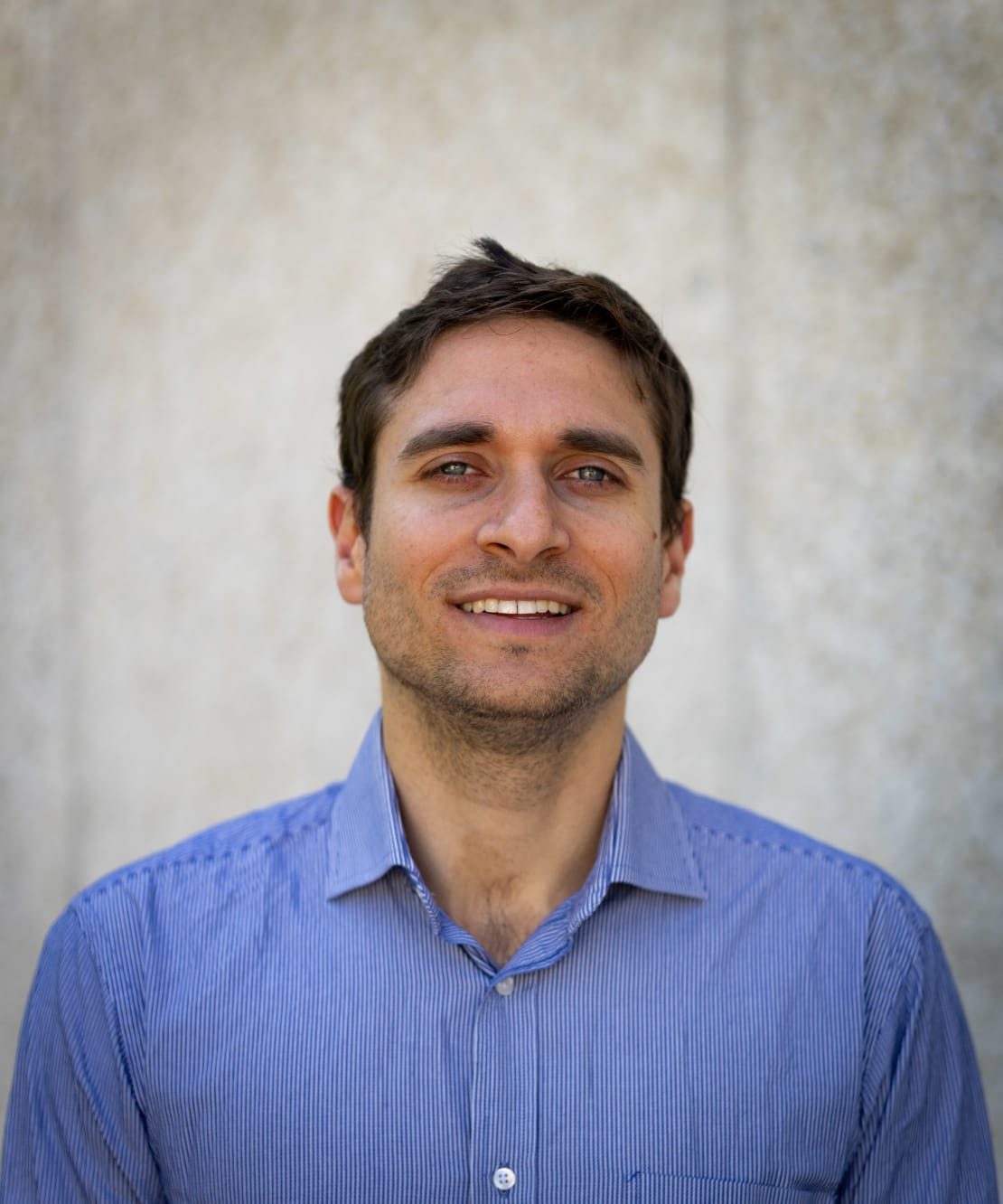 A headshot of a man wearing a blue collared shirt.