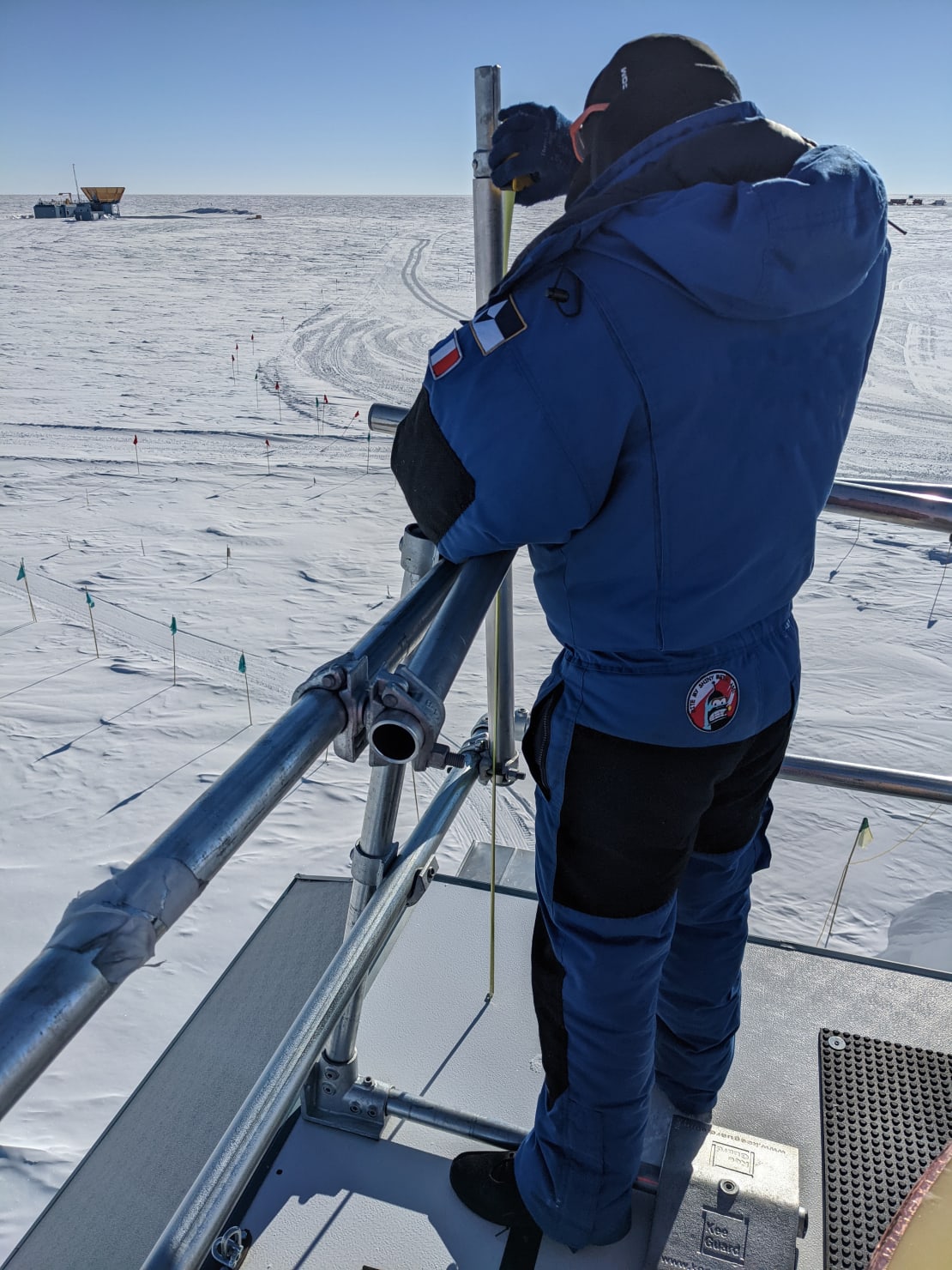 Winterover mounting a wind turbine on top of the IceCube Lab.