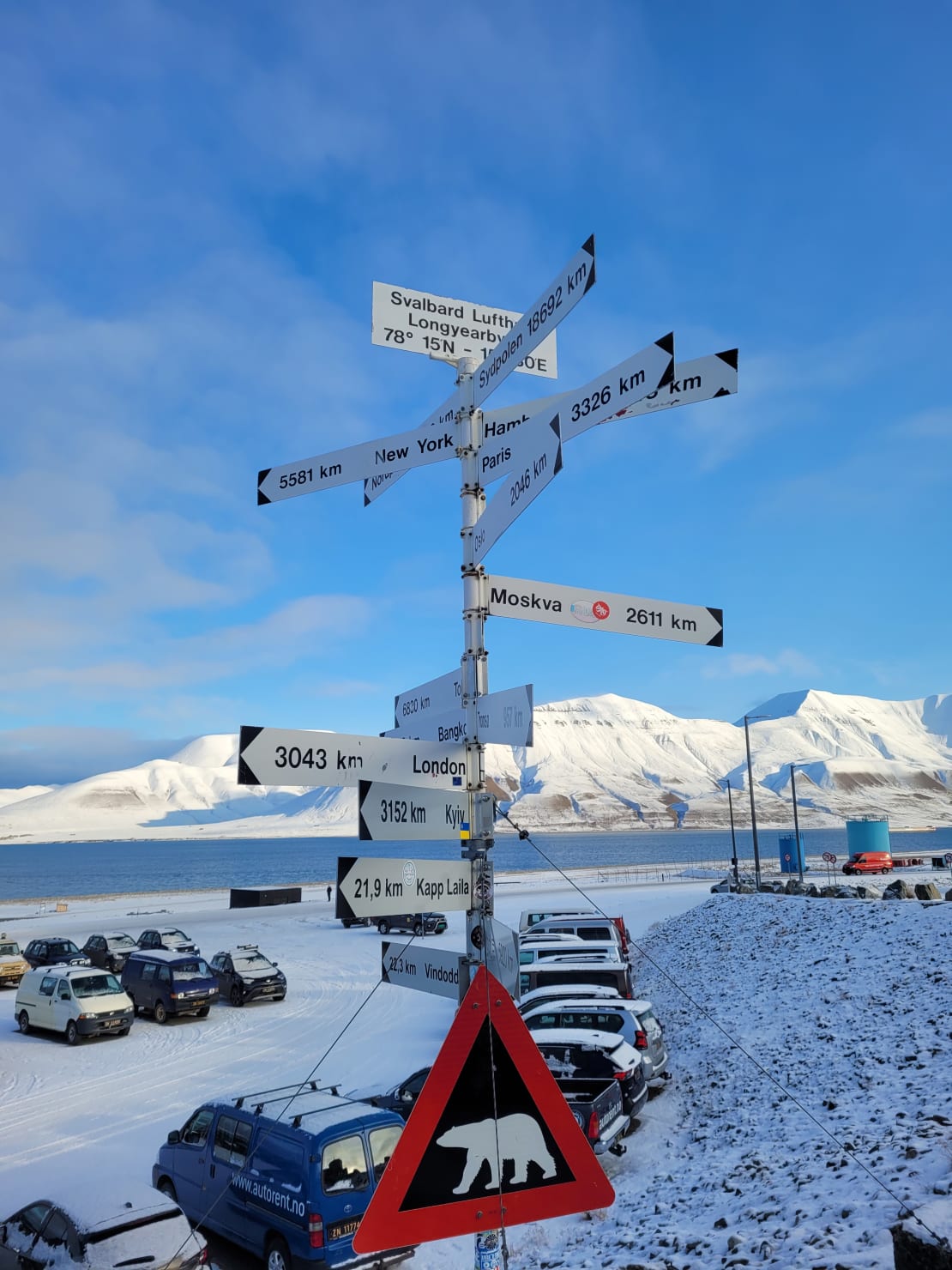 A sign with directions to different locations and a polar bear warning outside the Svalbard airport