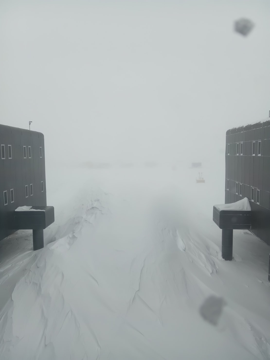 Tunnel view of drill camp seen from between two wings of the South Pole station under low-visibility conditions.