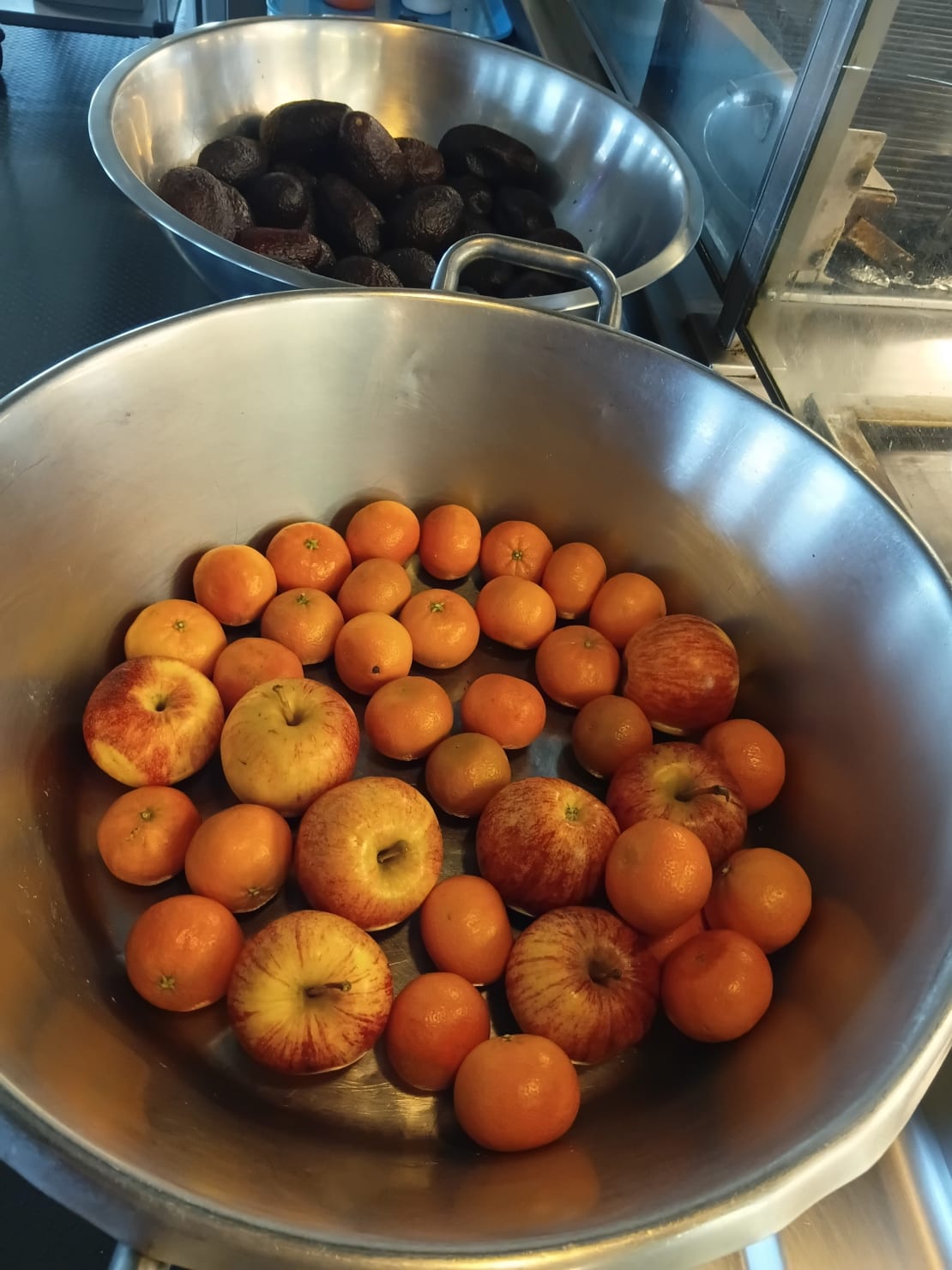 Two large metal bowls full of fresh fruit.