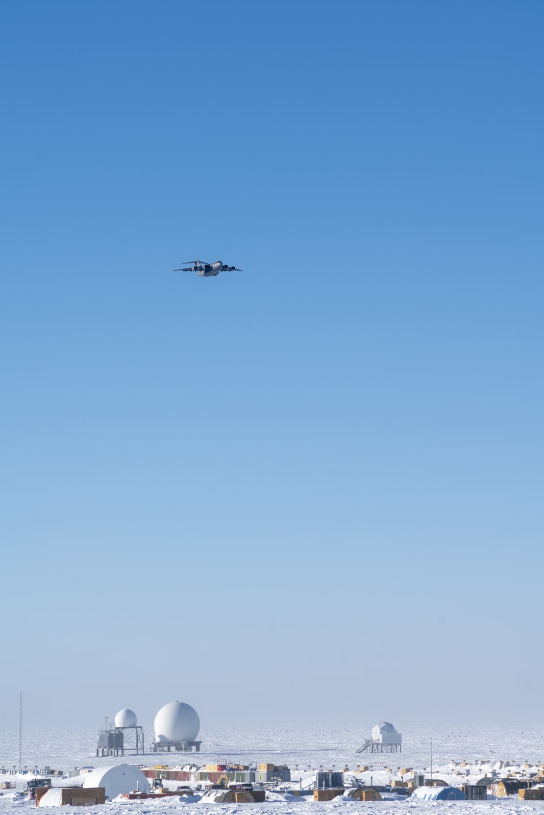 C17 flying above satellite domes at the South Pole.