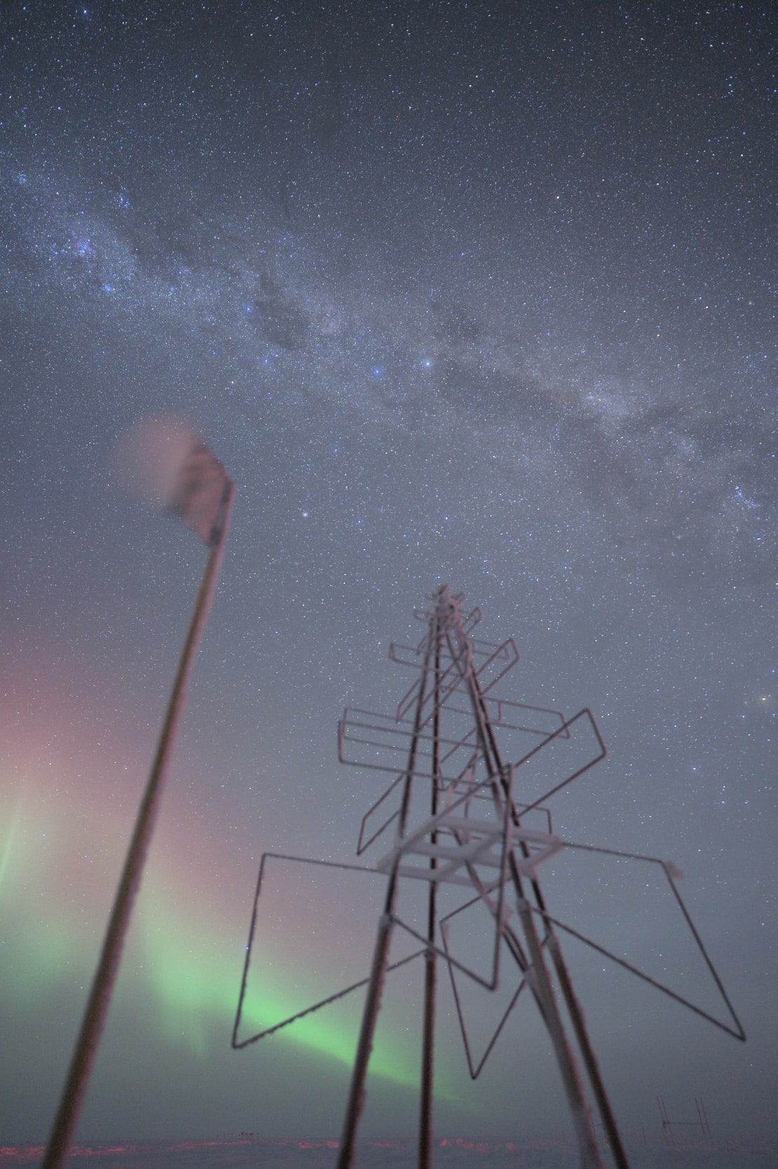 View looking up at tall frosty radio antenna, pointing toward Milky Way overhead.