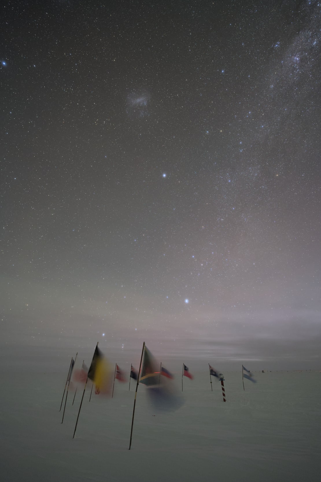 Starry sky above flags flapping in the wind at ceremonial South Pole.