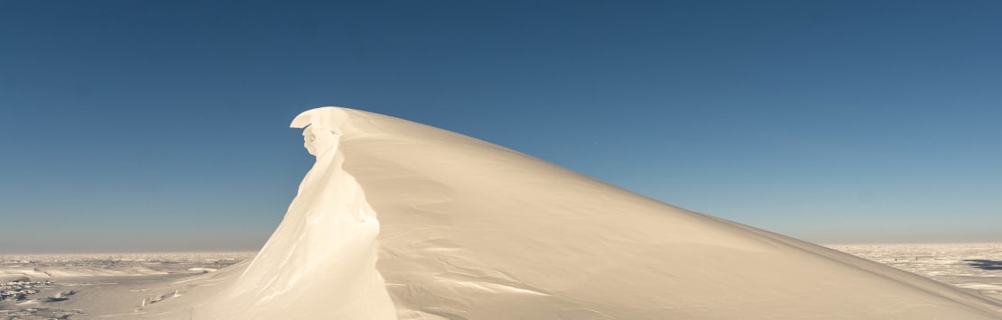 Large sunlit snowdrift against crisp blue sky.