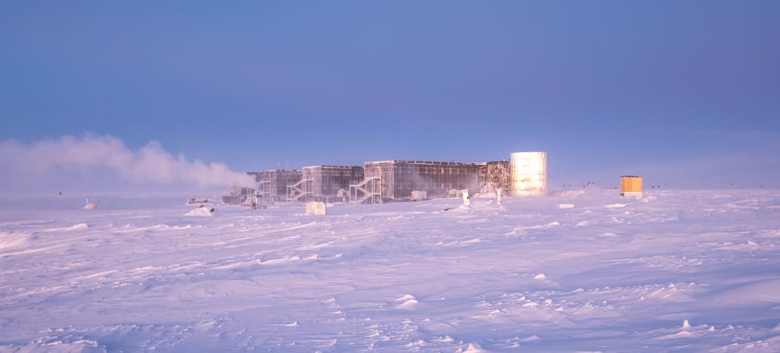The South Pole station in the distance, lit up with lingering light a few days past sunset.