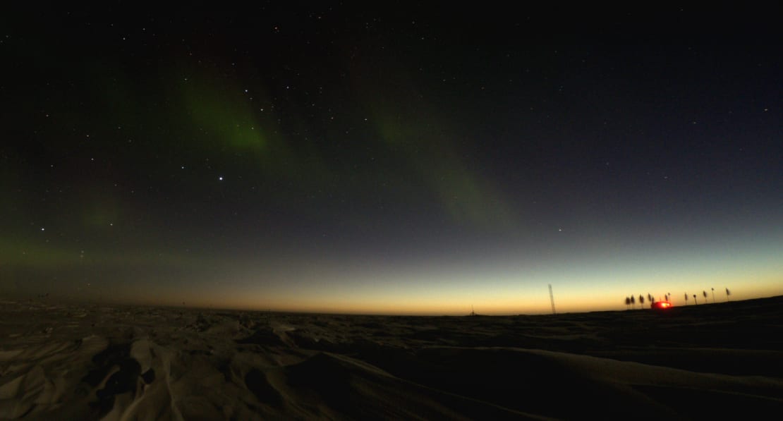 Wide view at the South Pole as yellowish light appears along horizon.