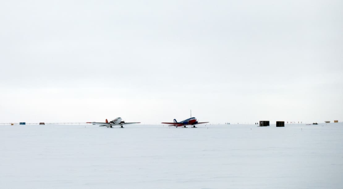 Two planes parked side by side on the ice at the South Pole.