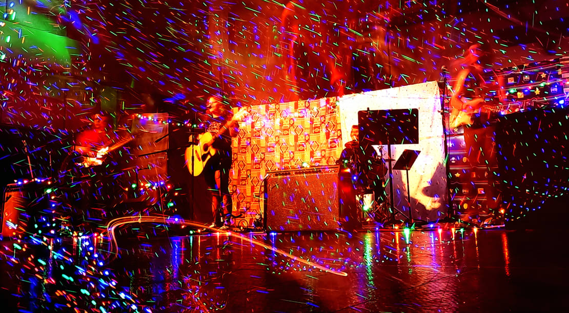 A band performing with lots of lines and swirls of colorful lights in motion