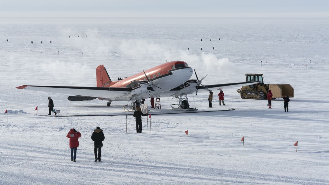 Arriving winter personnel walking away from plane parked on the skiway at South Pole.