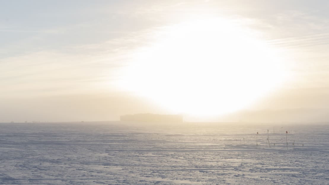 Bright sun low in sky over the South Pole station.