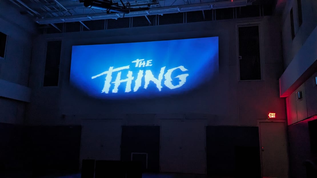 Large projection screen showing title image of The Thing.