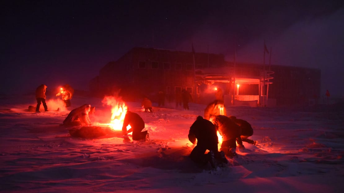 Several small teams crouched together outside under headlamp light.
