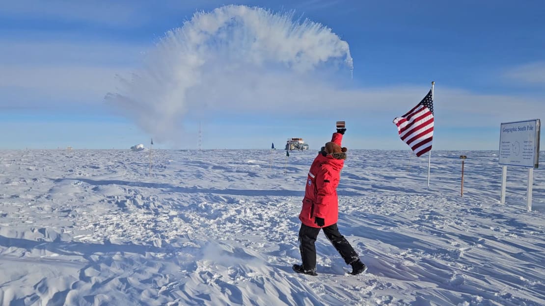 Spray of hot water turning to ice crystals overhead from winterover outside at the Pole throwing water into air.