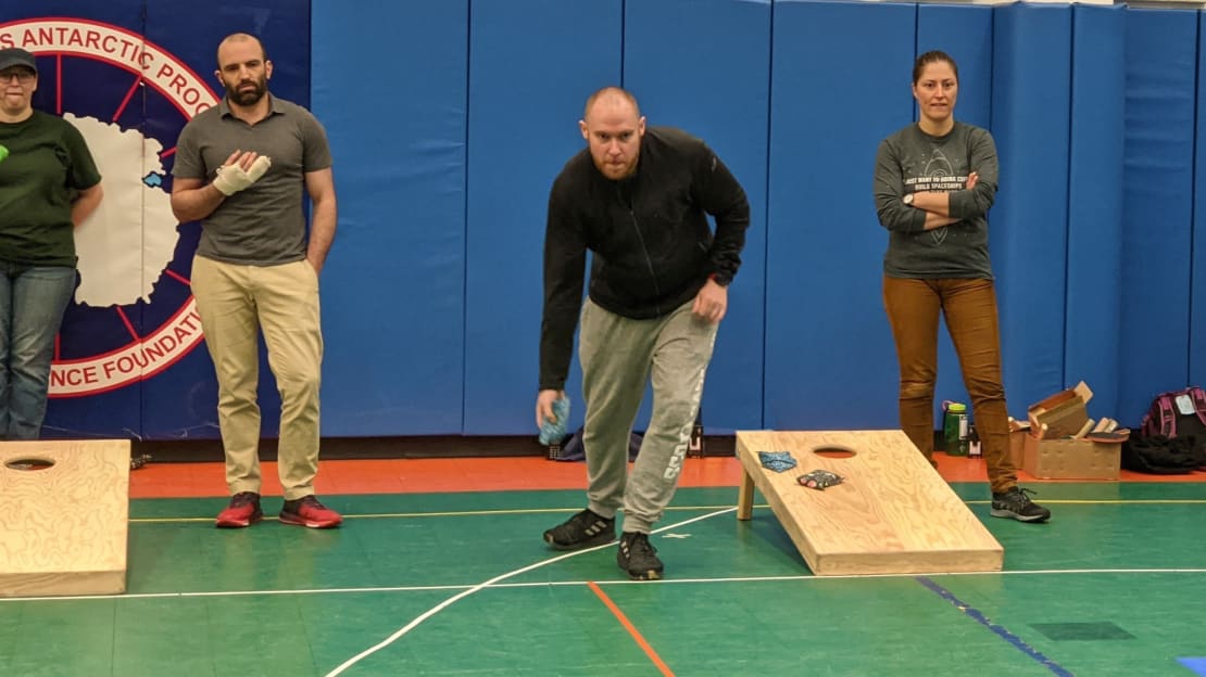 Action shot of people playing cornhole.