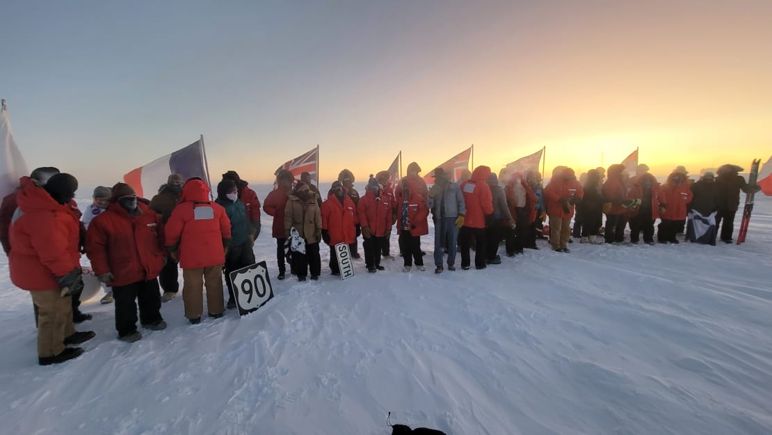 Winterovers preparing for group photo at ceremonial Pole flag circle at sunrise.