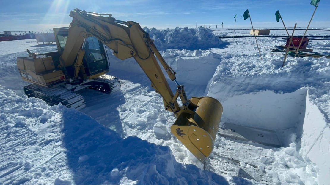 Heavy machinery excavating a pit in the ice.