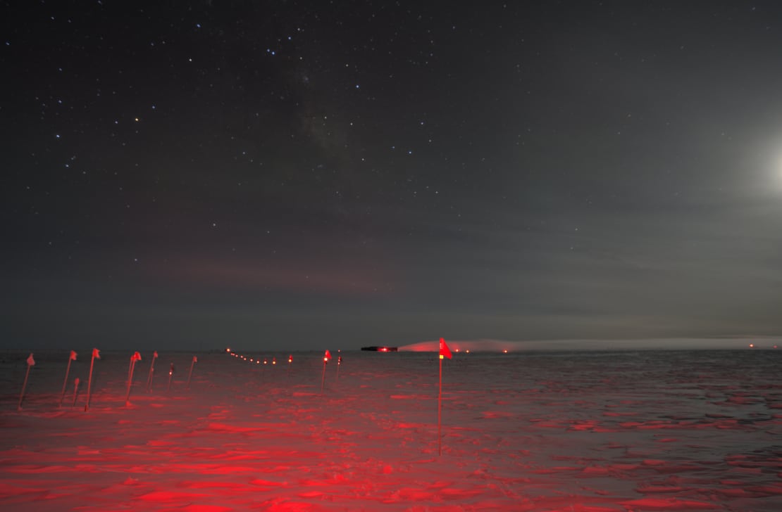 Reflective tops of flag line seen extending into distance under red headlamp light, also with moonlight coming from the side.