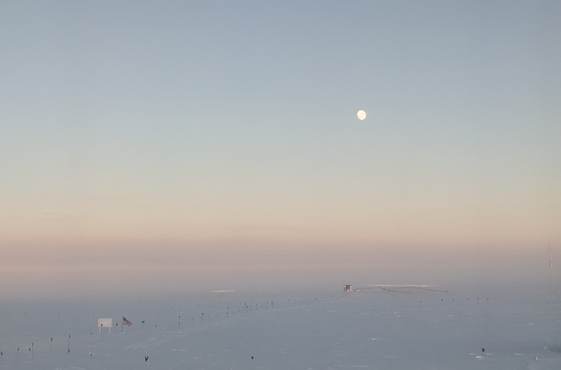 Rising moon high in the sky at the South Pole during sunset.