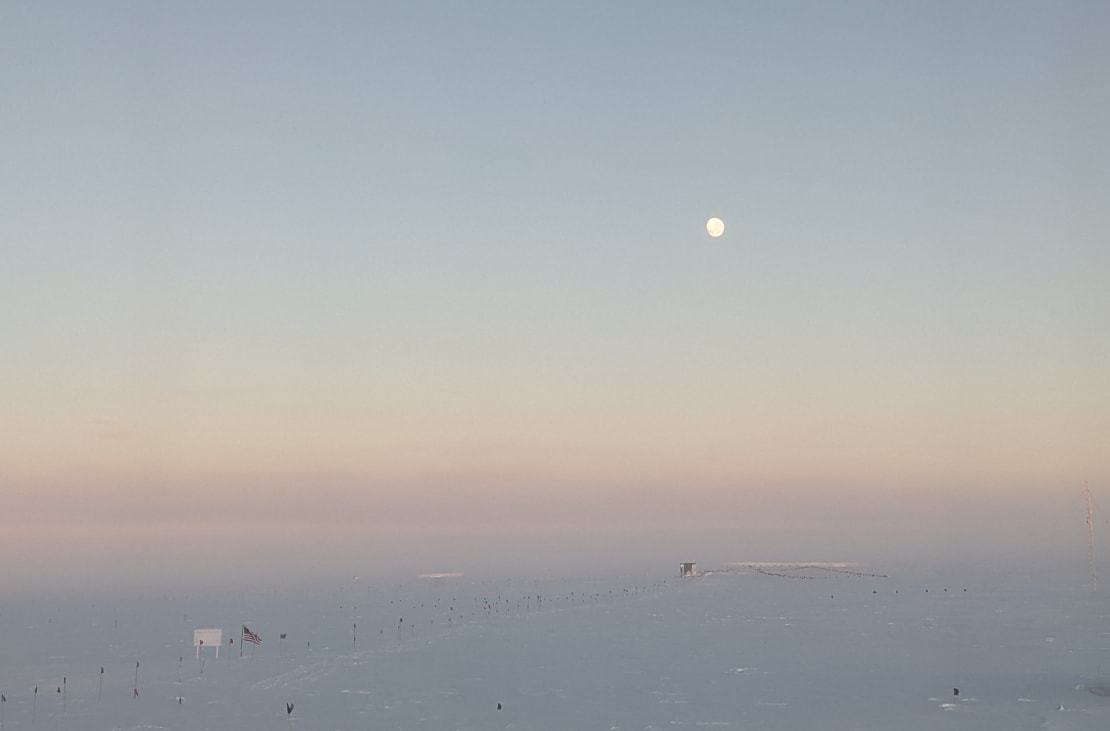 Rising moon high in the sky at the South Pole during sunset.